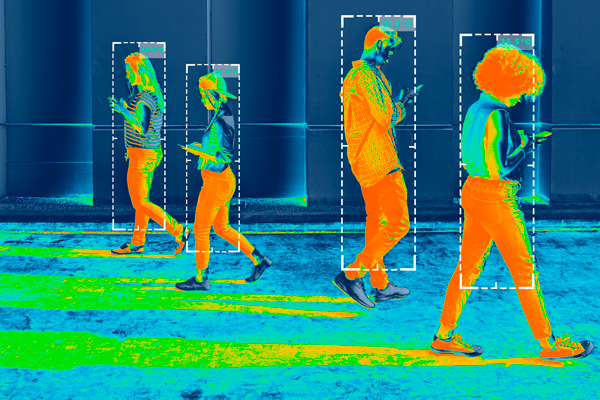 four people walking in a building while looking at mobile phones as captured by a thermal camera